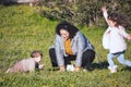 A young family playing outdoors on the green grass in a meadow - mother and little girl and boy Royalty Free Stock Photo