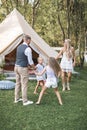 Young family is playing together on a sunny day in park. Father, mother and two daughters in casual boho clothes dancing Royalty Free Stock Photo