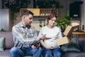 A young family, a pregnant woman and a man accidentally received someone else`s parcel. They opened the box, disappointed. Sittin Royalty Free Stock Photo