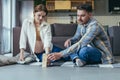 Young family. Pregnant woman and man sitting on the floor at home playing board game together. Make a tower of wooden bars. Have Royalty Free Stock Photo