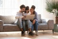 Young parents relax on couch using laptop with little daughter Royalty Free Stock Photo