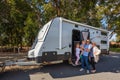 A Young Family proudly standing outside of their caravan in front of a Park