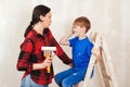 Young family renovating their home together. Mother and kid paint a wall with a paint roller Royalty Free Stock Photo