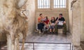 Young family rests on a bench in gallery of ancient sculpture, L