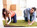 Young family rolling carpet at new apartment