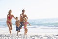 Young Family Running Along Beach on Holiday Royalty Free Stock Photo