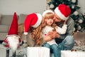 Young family in santa claus hat. Parents kiss their daughter.