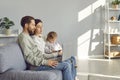 Family couple watching video on laptop while their little child is using tablet or mobile phone Royalty Free Stock Photo