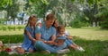 Young family sitting with tablet on sunny park. Happy people use laptop outdoors Royalty Free Stock Photo