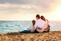 Young family sitting together in late afternoon sun on beach Royalty Free Stock Photo