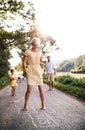 A young family with small children playing hopscotch on a road in summer.