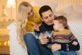 Young family spend time at home in Christmas time. Happy Mom, dad and son enjoyng love hugs, holidays people Royalty Free Stock Photo