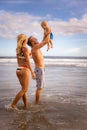 Young family spending summer vacation in Asia. Father holding, lifting his infant baby boy son high in the air. Beach concept. Royalty Free Stock Photo