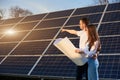 Young family is standing with plan in their hands and watching how solar panels are charging on site near at home Royalty Free Stock Photo