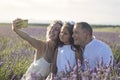 Young family with their daughter taking pictures with their mobile phone, in a beautiful lavender field.