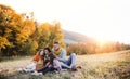 A young family with two small children having picnic in autumn nature at sunset. Royalty Free Stock Photo