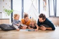 Young family with two small children indoors in bedroom reading a book. Royalty Free Stock Photo