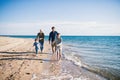 Young family with two small children running outdoors on beach. Royalty Free Stock Photo