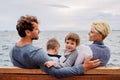 Young family with two small children sitting on bench outdoors on beach. Royalty Free Stock Photo