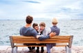 Young family with two small children sitting on bench outdoors on beach. Royalty Free Stock Photo