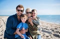 Young family with two small children sitting outdoors on beach. Royalty Free Stock Photo