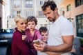 A young family with two small children standing outdoors in town, taking selfie. Royalty Free Stock Photo