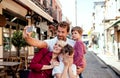 A young family with two small children standing outdoors in town, taking selfie. Royalty Free Stock Photo