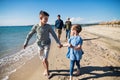 Young family with two small children walking outdoors on beach. Royalty Free Stock Photo