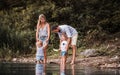 Young family with two toddler children outdoors by the river in summer, playing. Royalty Free Stock Photo