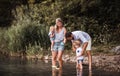 Young family with two toddler children outdoors by the river in summer, playing. Royalty Free Stock Photo