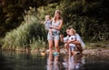 Young family with two toddler children outdoors by the river in summer, playing. Royalty Free Stock Photo