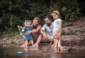 A young family with two toddler children outdoors by the river in summer. Royalty Free Stock Photo