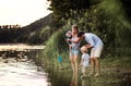 A young family with two toddler children outdoors by the river in summer. Royalty Free Stock Photo