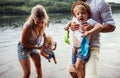 A young family with two toddler children outdoors by the river in summer. Royalty Free Stock Photo