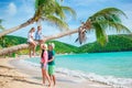 Little girls having fun sitting on the palm tree. Happy family relaxing on tropical beach with white sand and turquoise Royalty Free Stock Photo