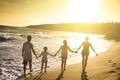 young family walking on beach at sunset Royalty Free Stock Photo