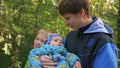 Young family walking in the park, father carrying son in his arms