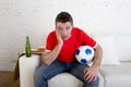 Young fan man watching football game on television wearing team jersey suffering nervous and stress