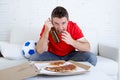 Young fan man watching football game on tv wearing team jersey suffering nervous and stress Royalty Free Stock Photo