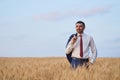 Young farmer businessman in shirt and tie inspects his fields with crops