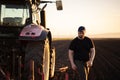 Farmer examing dirt while tractor is plowing field