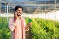 young farmer at greenhouse talking on mobile phone call by holding green credit card - conept of online payment Royalty Free Stock Photo