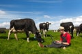 Young farmer with laptop in field with cows