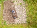 Young farmer man is cultivating the field with machine. Aerial drone top down view of small field in old fashioned garden. Concept