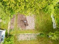 Young farmer man is cultivating the field with machine. Aerial drone top down view of small field in old fashioned garden. Concept