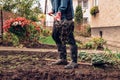 Young farmer with red glovews carries a piece of manure on forks and throws it into the soil to replenish nutrients. Agricultural