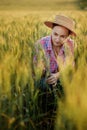A young farmer sits in the ears of wheat and analyzes here growth