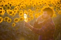 Young farmer standing in the middle of a golden sunflower field talking on phone while holding up a sunflower oil bottle during a Royalty Free Stock Photo