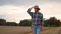 Young farmer walking through golden wheat field and enjoying of the quality of harvest