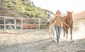 Young farmer woman preparing her horses for training - Cowgirl having fun in ranch farm outdoor - Concept about love between Royalty Free Stock Photo